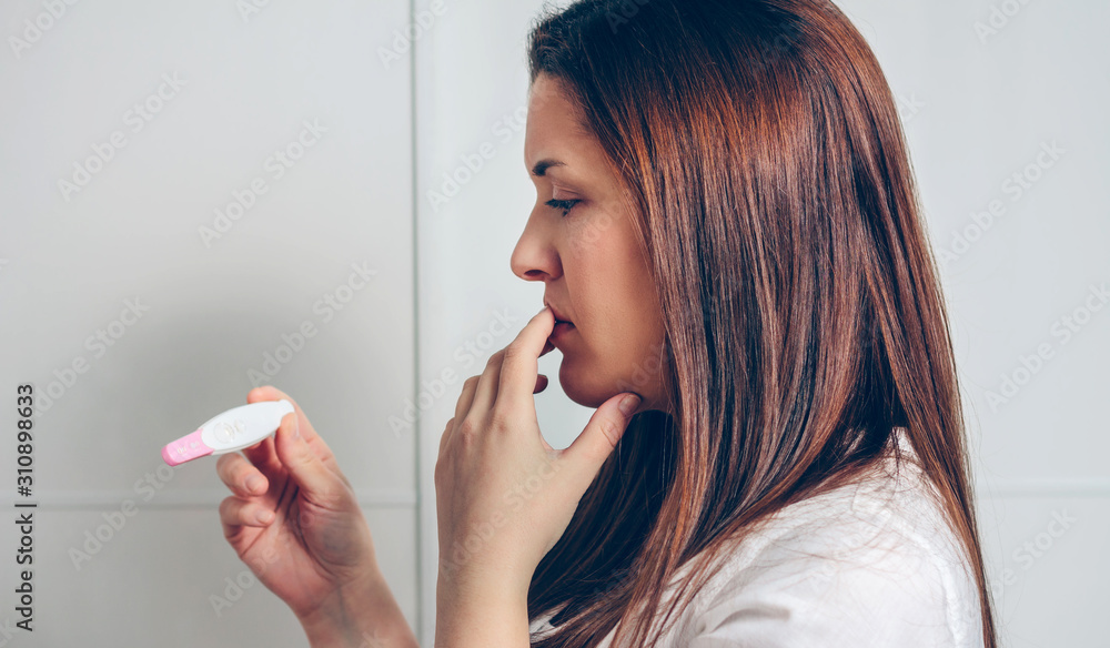 Worried pregnant woman looking at a pregnancy test