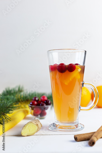 Orange and cranberry punch with orange slices and spices on a white table. Hot drinks for winter and Christmas