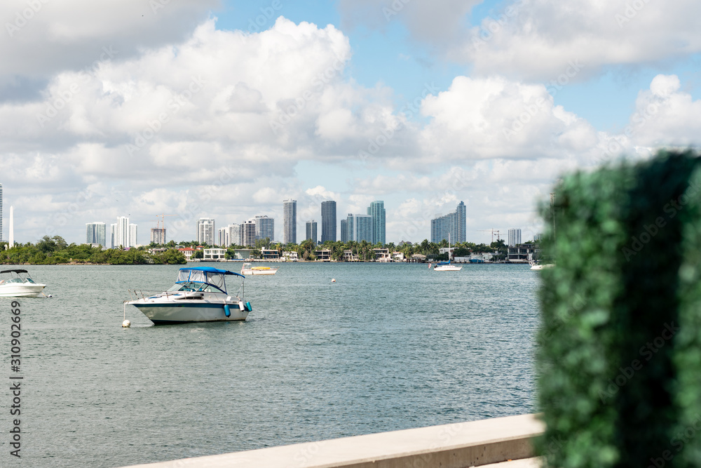 Naklejka premium a boat travels through a harbor headed away from the city line of downtown Miami, Florida on a bright sunny morning