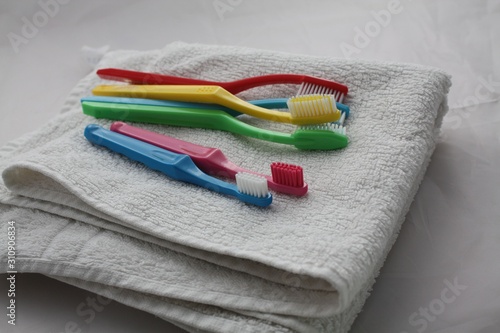 Colorful toothbrushes laying on a white towel. Dental care in family, bathroom, teeth hygiene concept.