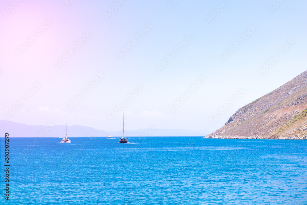 Beautiful seascape with calm blue Mediterranian sea, mountains in mist and boat, touristic season, vacation on sunny islands