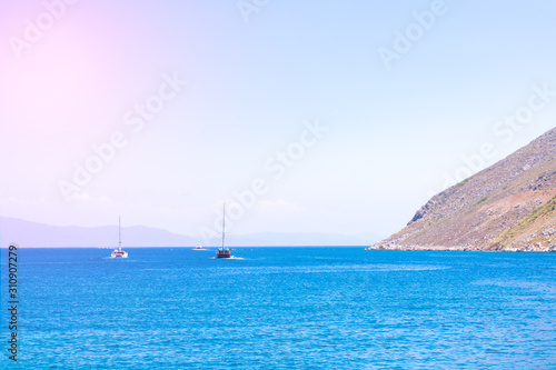 Beautiful seascape with calm blue Mediterranian sea, mountains in mist and boat, touristic season, vacation on sunny islands