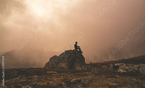 Contemplative Silhouette Sitting On Rock In Nature photo
