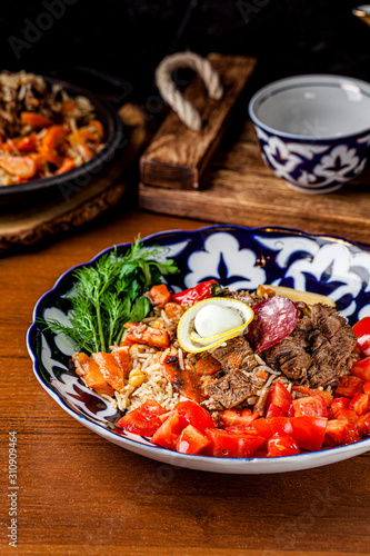 Traditional oriental cuisine. Uzbek, Samarkand pilaf with vegetables and green potatoes. Serving dishes in Uzbek plates. Copy space, background image