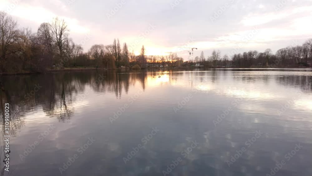 Placid lake water and reflections with sunset at background Placid lake water and reflections with sunset at background