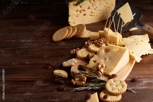 Pieces of cheese, nuts, raisins, snacks for wine on a wooden background. Appetitive photo