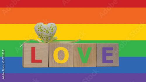 Wooden cubes with word LOVE and white heart on rainbow flag background. Valentines and LGBT isolated concept. photo