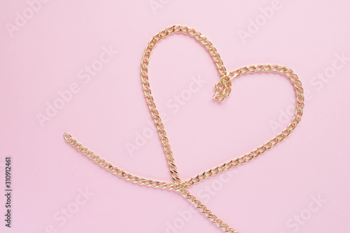 a gold chain laid out in the shape of a heart on a pink background