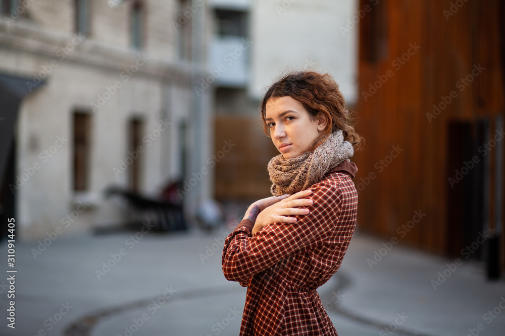 Dreaming young woman with spectacular curly red ginger hair looking at camera posing outdoor in downtown street. Female portrait. Dreaming young woman with spectacular curly red ginger hair looking at camera posing outdoor in downtown street. Female portrait.