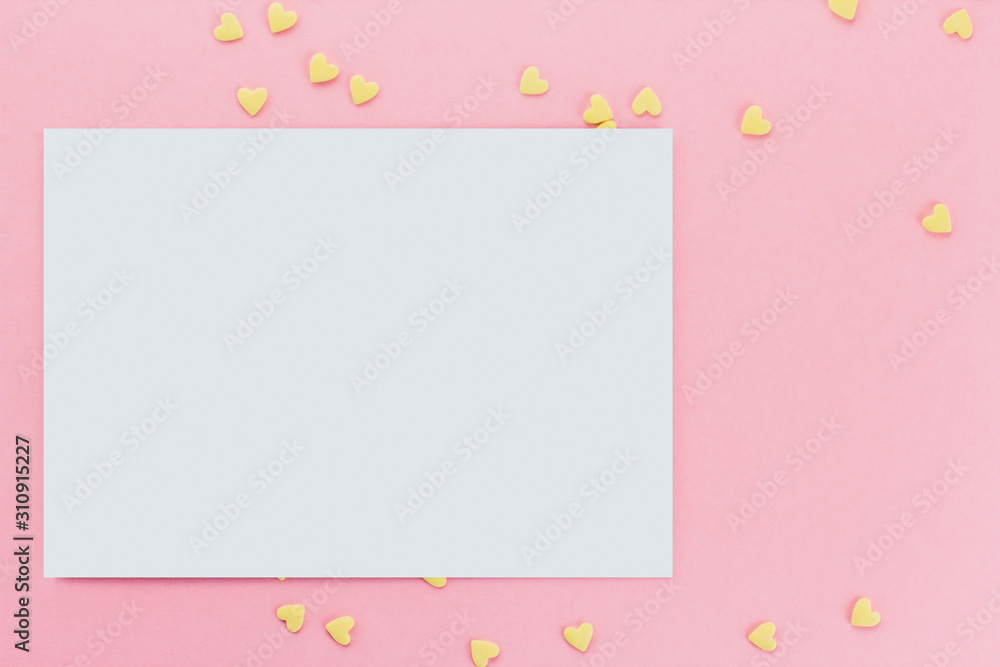 card on a background of heart-shaped confectionery confetti on a pink background copy space. Yellow hearts.