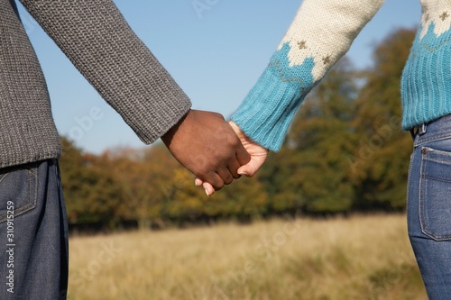 Multiethnic Couple Holding Hands In Field