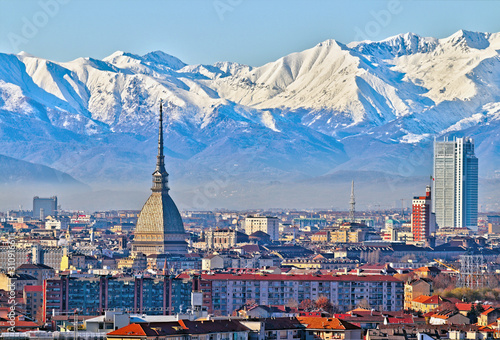 Aerial panoramic winter view on Turin city center with Mole Antonelliana  modern skyscrapers and other buildings  clear blue sky morning with Alps full of snow on background