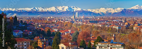 Aerial panoramic winter view on Turin city center with Mole Antonelliana, modern skyscrapers and other buildings, clear blue sky morning with Alps full of snow on background