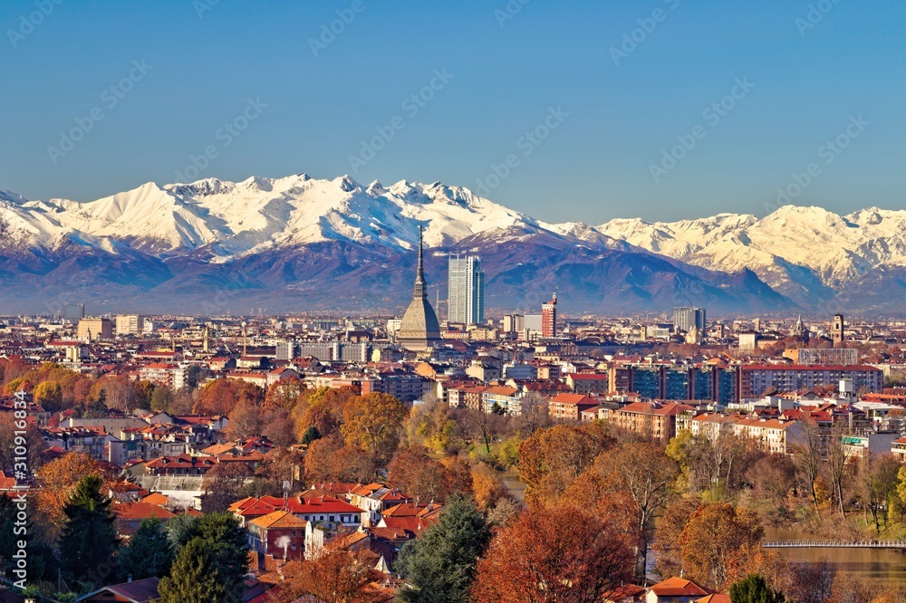 Aerial panoramic winter view on Turin city center with Mole Antonelliana, modern skyscrapers and other buildings, clear blue sky morning with Alps full of snow on background