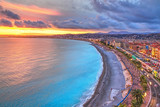 Impressive sunset view of Nice sea waterfront from the castle hill, with tumultuous sky and clouds, and warm light