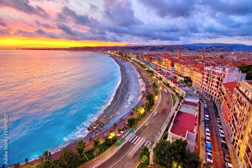 Impressive sunset view of Nice sea waterfront from the castle hill, with tumultuous sky and clouds, and warm light