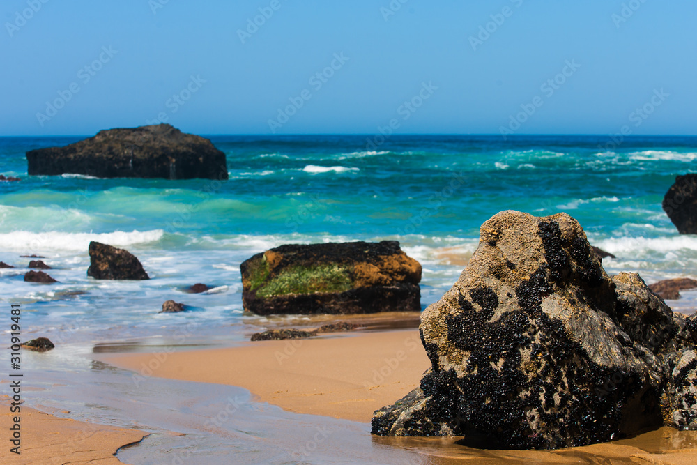 Rocky beach at sunrise, Atlantic ocean coast, Adraga, Portugal. Travel and business background