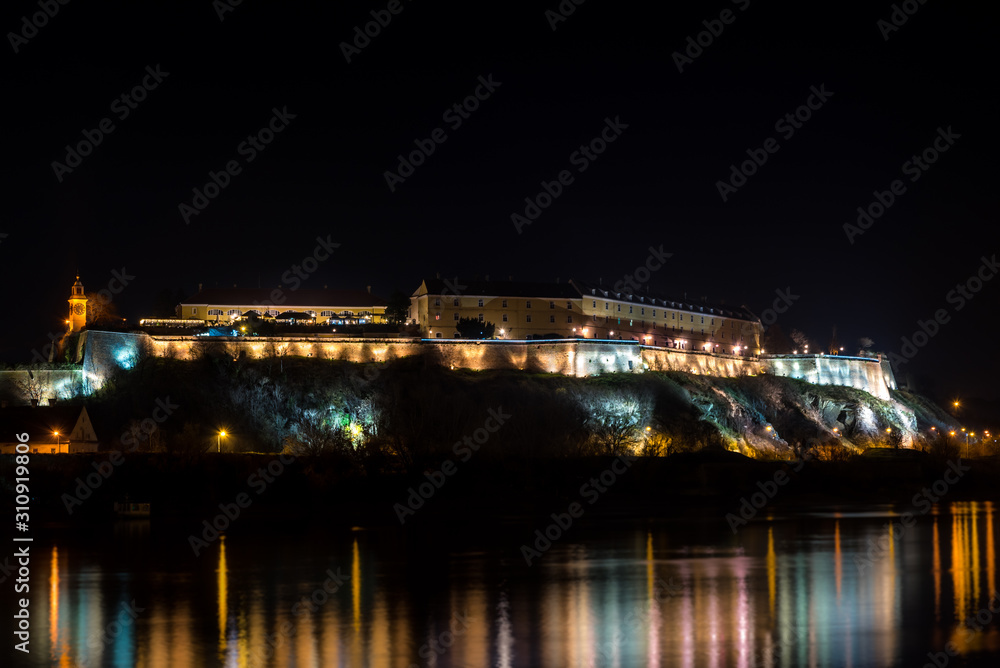 Petrovaradin fortress in Novi Sad, Serbia illuminated with colorful street lights and reflection in the Danube river water night image