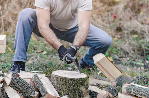 Man chopping wood with an ax, parts of logs scatter to sides
