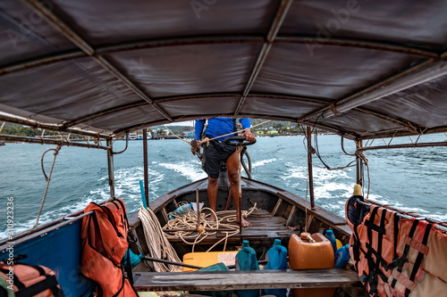 Inside in thai longtail boat. View of empty seats for passengers and life jackets. The sailor controls the boat and sails from the shore to the sea