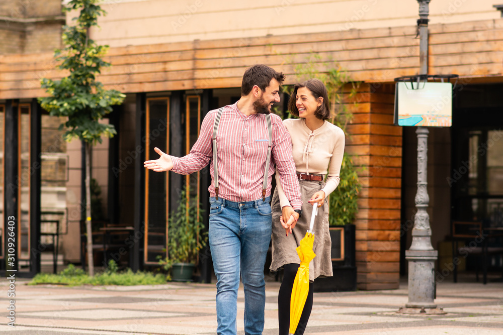 Fototapeta premium A man and a woman on the street walking and talking holding hands with fingers entwined,smiling.