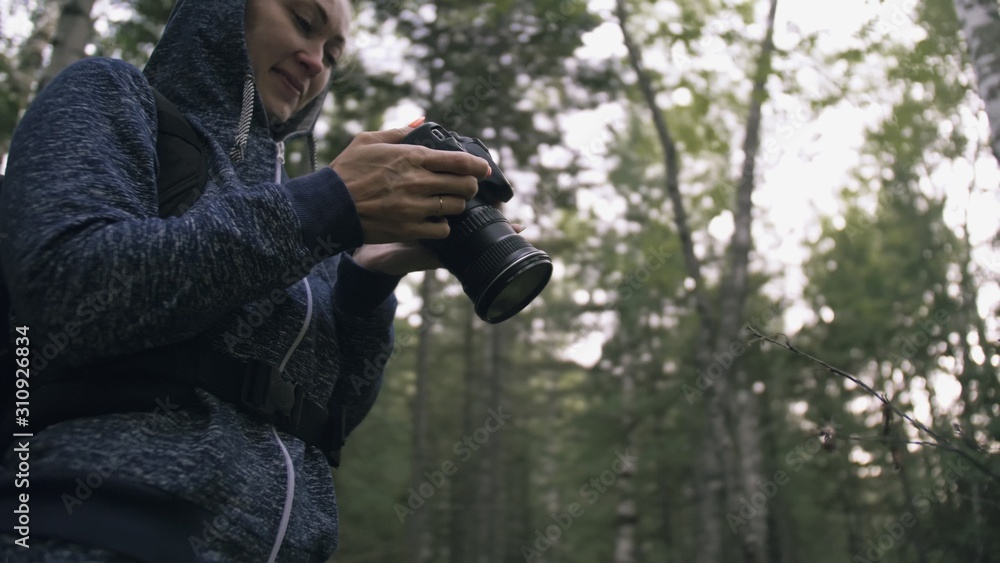 Traveler photographing scenic view in forest. One caucasian woman shooting close up look. Girl take photo video on dslr mirrorless camera. Professional photographer travel with backpack. Outdoor. Traveler photographing scenic view in forest. One caucasian woman shooting close up look. Girl take photo video on dslr mirrorless camera. Professional photographer travel with backpack. Outdoor.