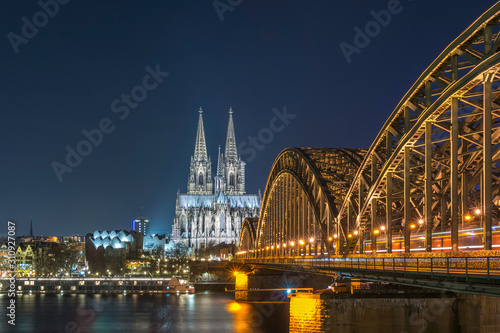 Illuminated Cologne Cathedral and Hohenzollern Bridge at night 