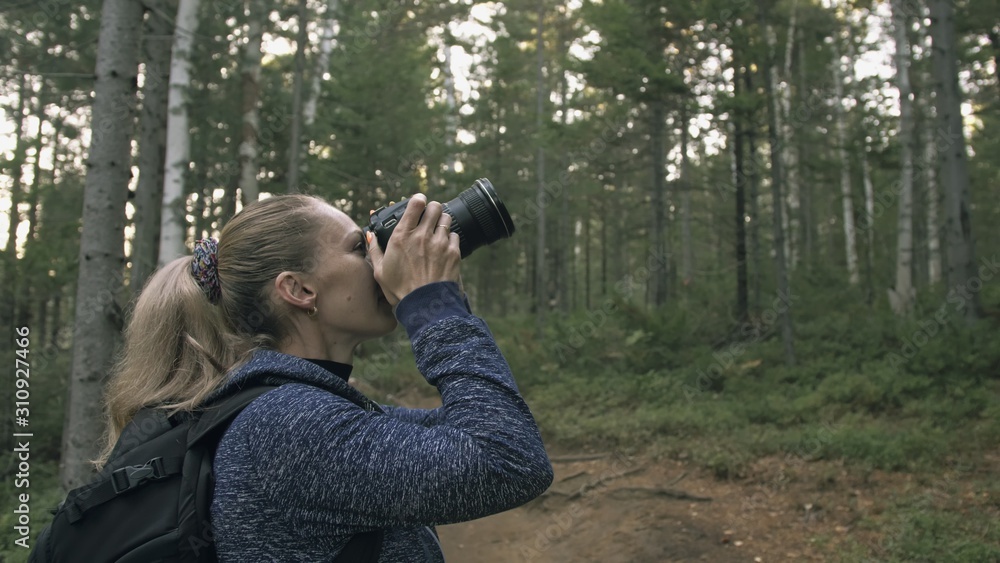 Traveler photographing scenic view in forest. One caucasian woman shooting nice magic look. Girl take photo video on dslr mirrorless camera. Professional photographer travel with backpack. Outdoor. Traveler photographing scenic view in forest. One caucasian woman shooting nice magic look. Girl take photo video on dslr mirrorless camera. Professional photographer travel with backpack. Outdoor.