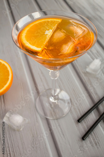 Aperol spritz cocktail in martini glass on the grey wooden background. Location vertical. Copy space.