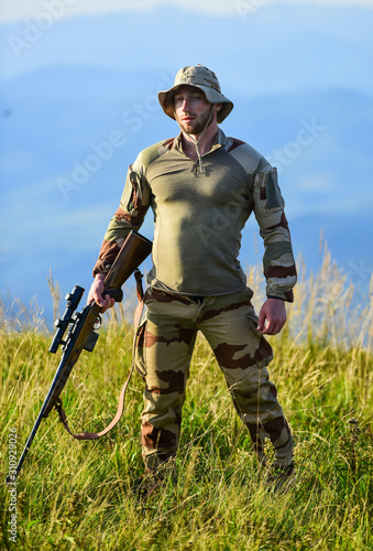 Ready to shoot. Army forces. Man military clothes with weapon. Focus and concentration experienced hunter. Brutal warrior. Rifle for hunting. Hunter hold rifle. Hunter mountains landscape background