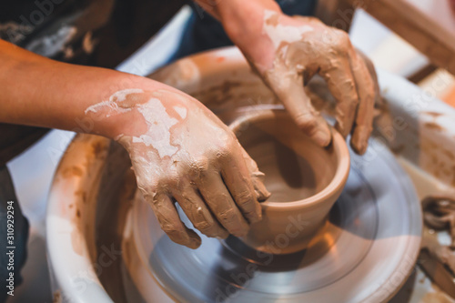 Teenager girl behind a potter's wheel. Hands close up.