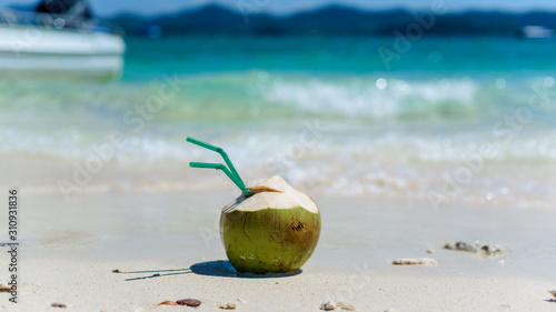 Drinking coconut with two straws on a tropical beach.