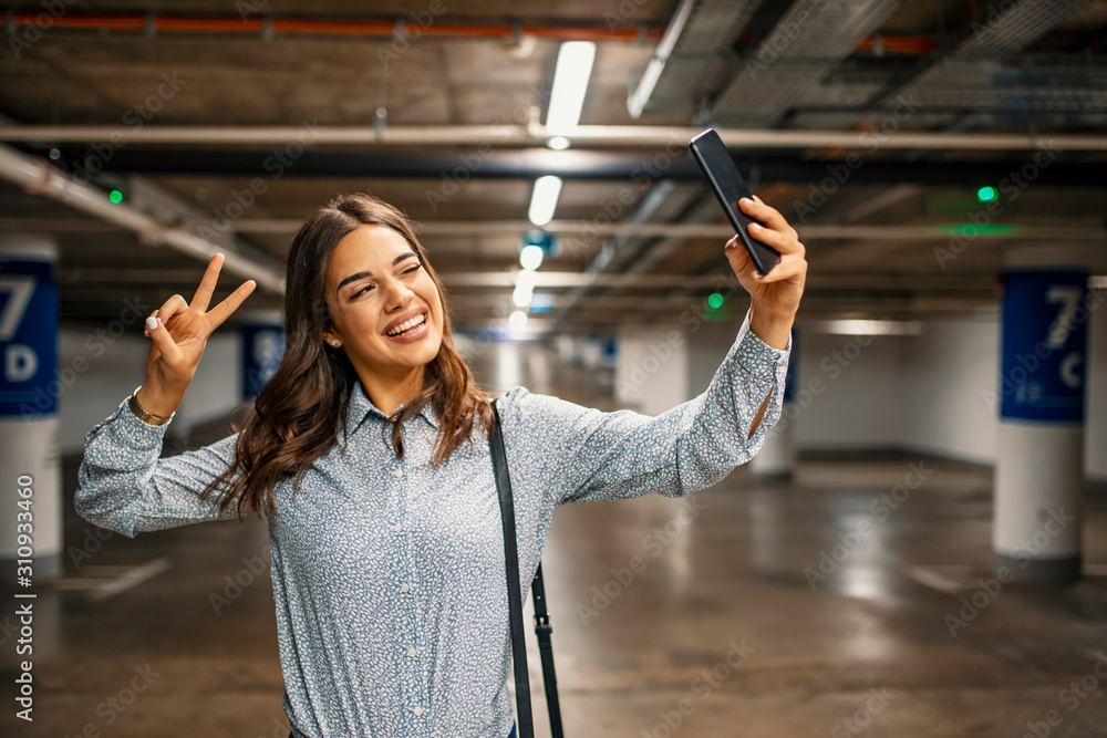 Elegant woman taking selfie in underground parking garage. Self ...