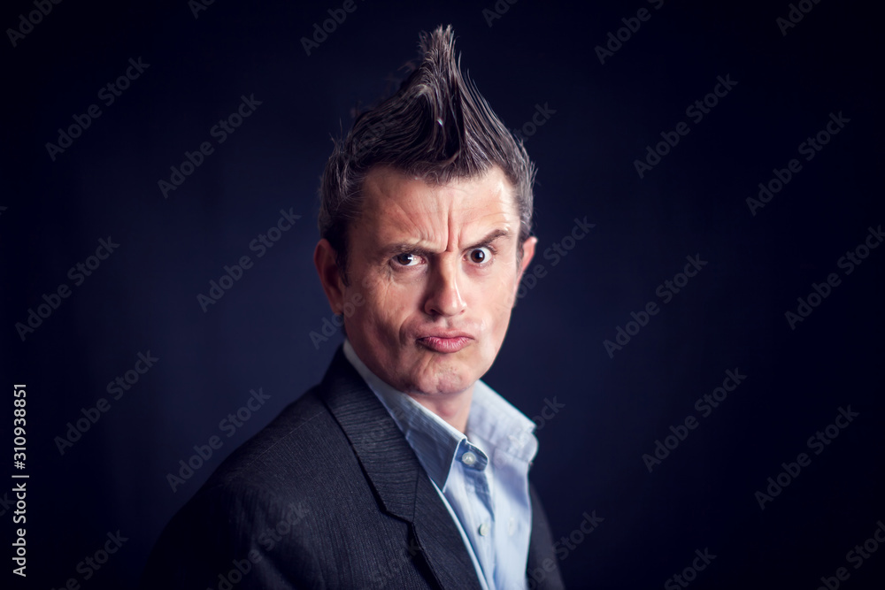 Man with mohawk wearing suit in front of black background. Man with mohawk wearing suit in front of black background.