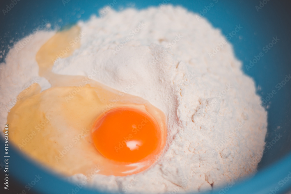 Fresh chiken egg in flour ready for mixing and baking, close up shot Fresh chiken egg in flour ready for mixing and baking, close up shot