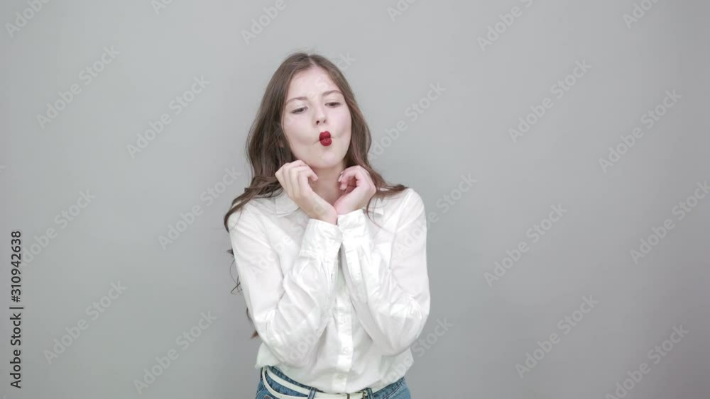 Shocked caucasian young woman in fashion white shirt holding hands on cheek with opened mouth, looking at camera isolated on gray background in studio. People sincere emotions, lifestyle concept. Shocked caucasian young woman in fashion white shirt holding hands on cheek with opened mouth, looking at camera isolated on gray background in studio. People sincere emotions, lifestyle concept.
