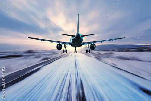 Landing of the passenger plane to the highway at winter evening time.