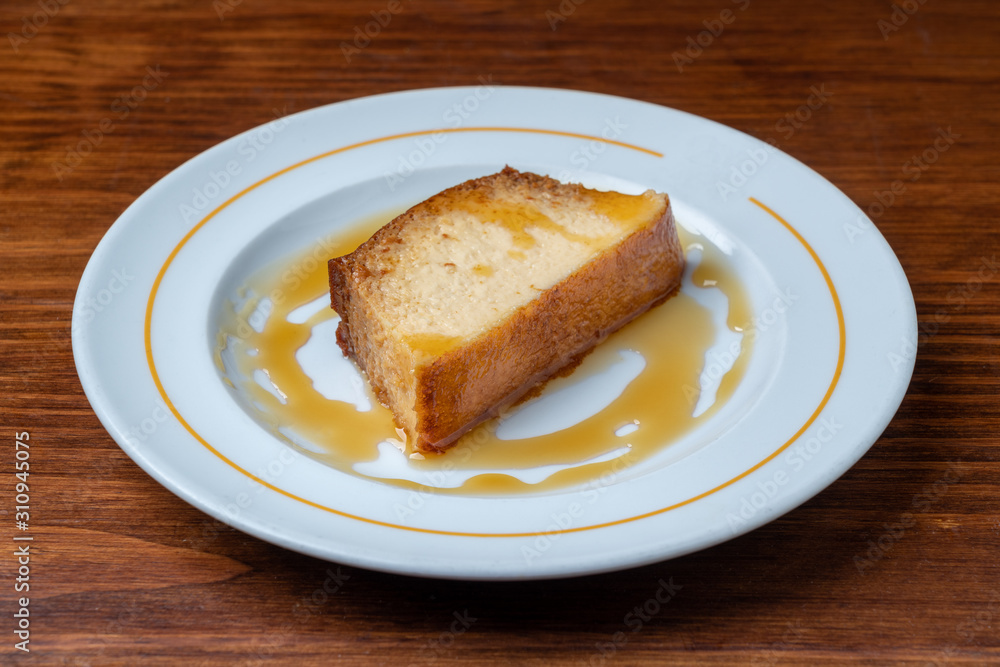 A slice of portuguese dessert caramel pudding. On a wooden table. A slice of portuguese dessert caramel pudding. On a wooden table.