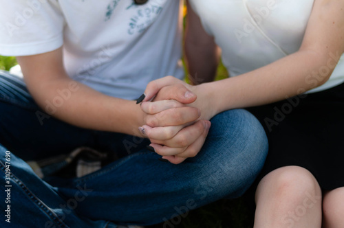 cropped view of man and woman sitting and holding hands in park
