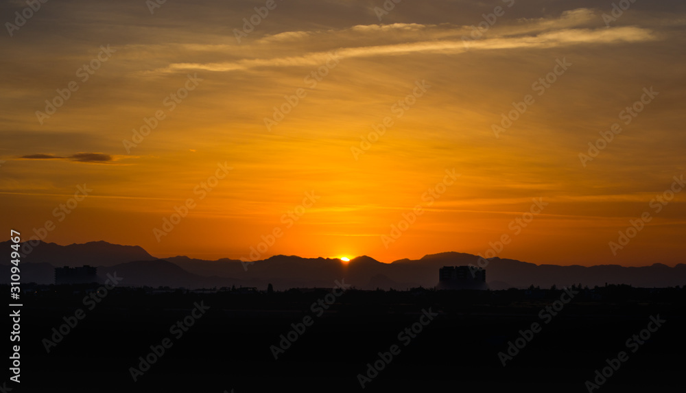 View of golden sky with the mountain silhouette in the time of lovely sunset over a city. View of golden sky with the mountain silhouette in the time of lovely sunset over a city.