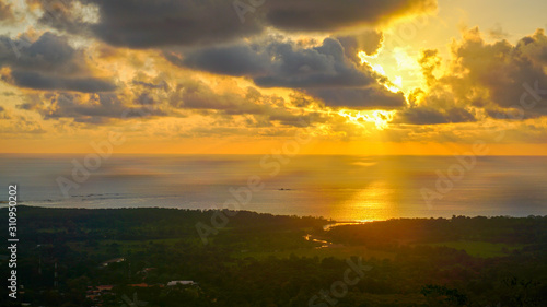 Spectacular sunset over the pacific while the sun's rays are breaking through the clouds over the ocean and the mainland. Amazing view over the jungle and the ocean with many tone colours on the sky.