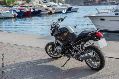 Motorcycle on the pier near moored yachts