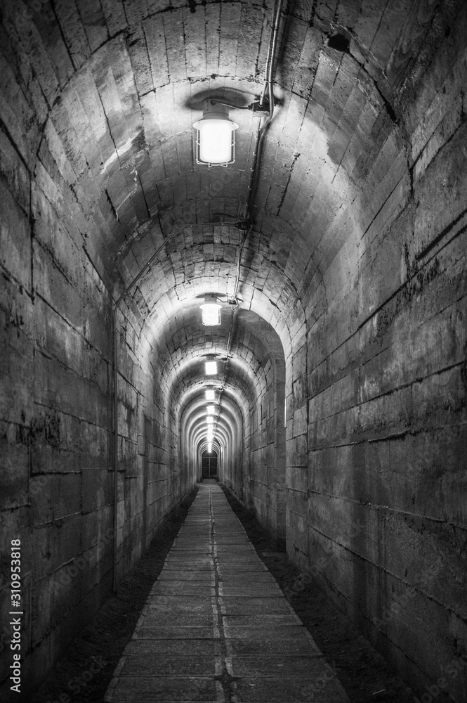 Illuminated, long underground tunnel made of concrete.