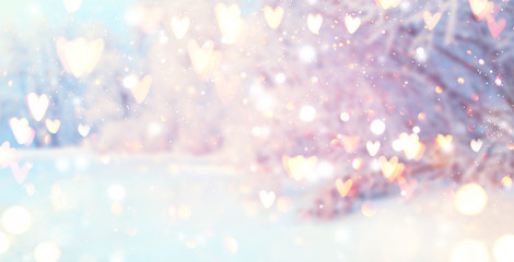 St. Valentine's Day winter blurred background with glowing hearts. Xmas trees with snow, holiday festive background. Widescreen backdrop. New year Winter art design with snowflakes. Nature scene