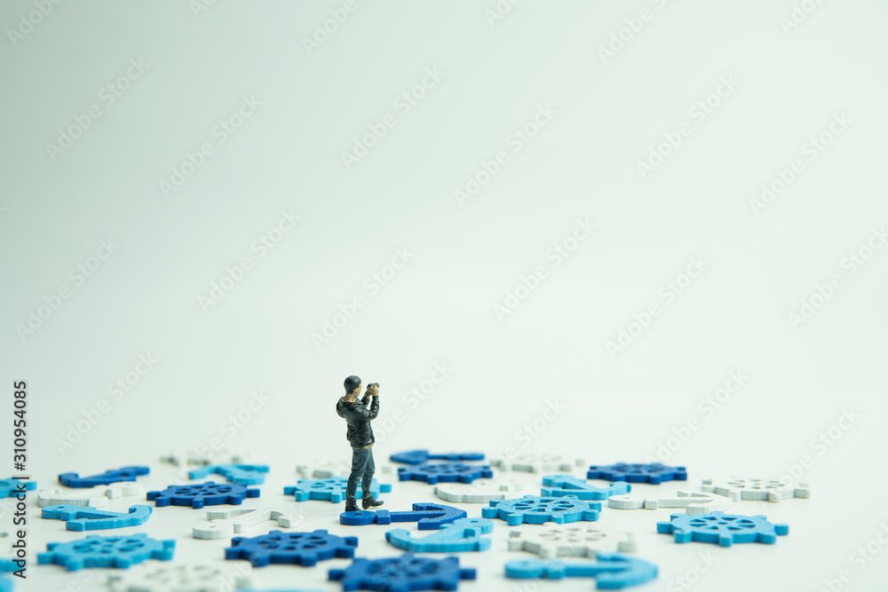 Selective focus of doll figure adult man satnding with camera, anchor and ship steer shape object.Main subject is doll figure. Selective focus of doll figure adult man satnding with camera, anchor and ship steer shape object.Main subject is doll figure.