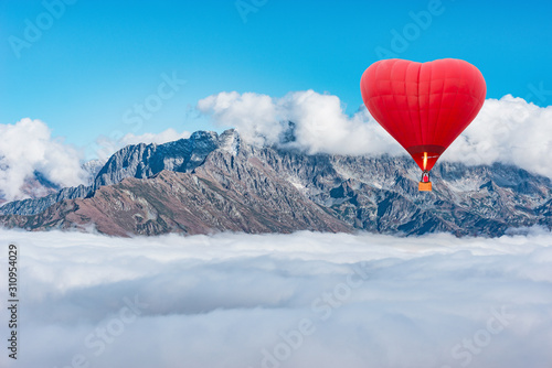 Morning flight of the hot air balloon above the mountains and clouds.