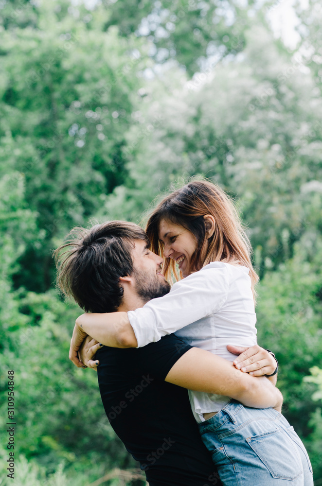 Happy couple kissing and hugging in nature. Young man and woman in loving relationship having fun in park. Happy couple kissing and hugging in nature. Young man and woman in loving relationship having fun in park.