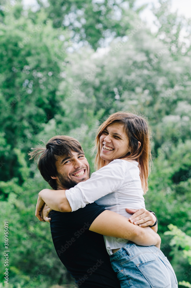 Happy couple kissing and hugging in nature. Young man and woman in loving relationship having fun in park. Happy couple kissing and hugging in nature. Young man and woman in loving relationship having fun in park.