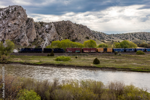 MAY 23 2019, USA - THREE FORKS, MT - Missouri River Breaks National Monument, the source of the Missouri River, freight train runs along river photo