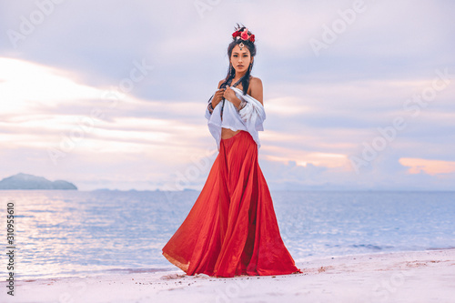 beautiful young stylish boho woman walking on the beach at sunset